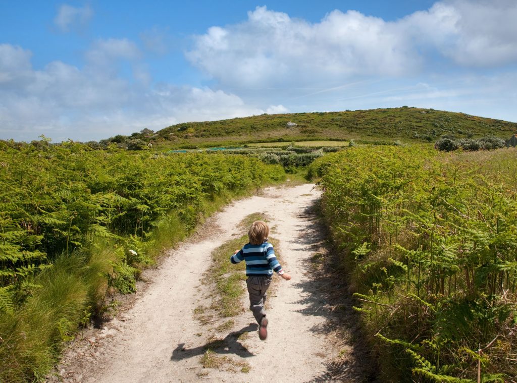 Boy running up a country track on Bryher, Isles of Scilly, Cornwall, England.