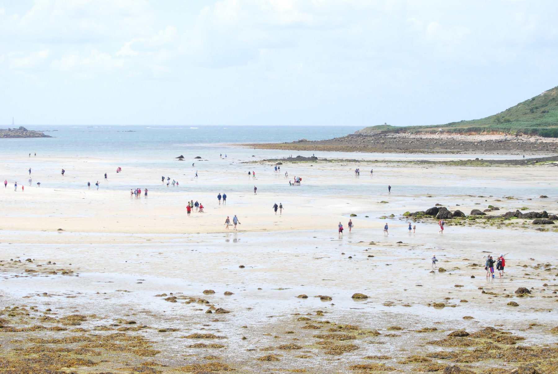 People walking across the channel between Tresco and Bryher on the Isles of Scilly at low tide